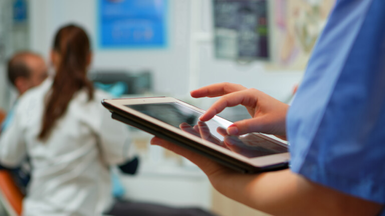 Close up of nurse holding and typing on tablet