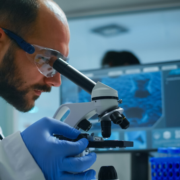 Lab technician examining samples and liquid using microscope