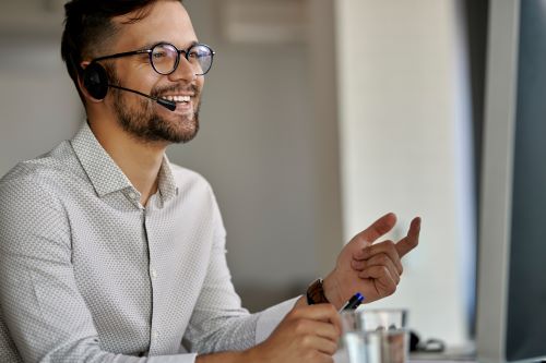 happy call center agent using computer while communicating with clients working office LR